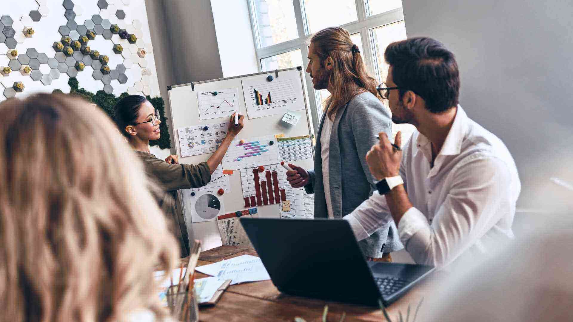 3 person team sharing ideas in front of a whiteboard