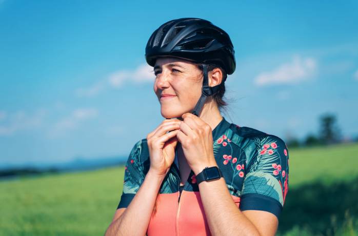 Woman cyclist putting on helmet