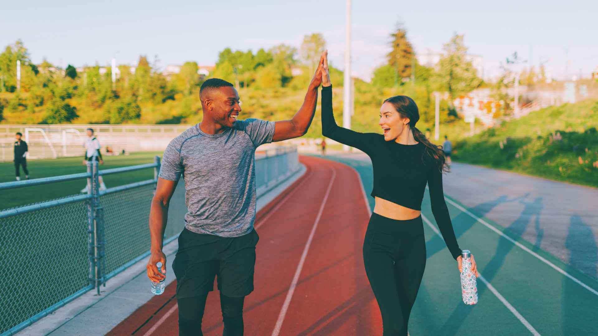 2 Athletic individuals Doing High Five Outdoors