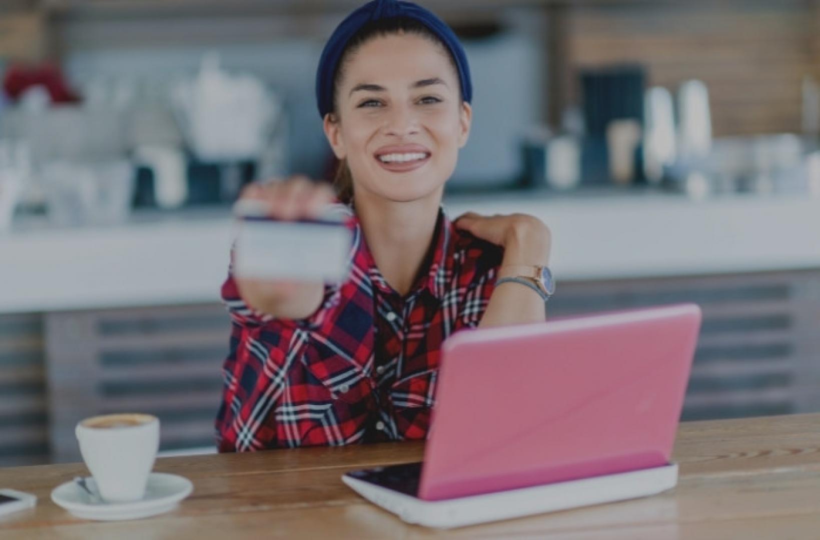 woman in front of her laptop holding her credit card in hands