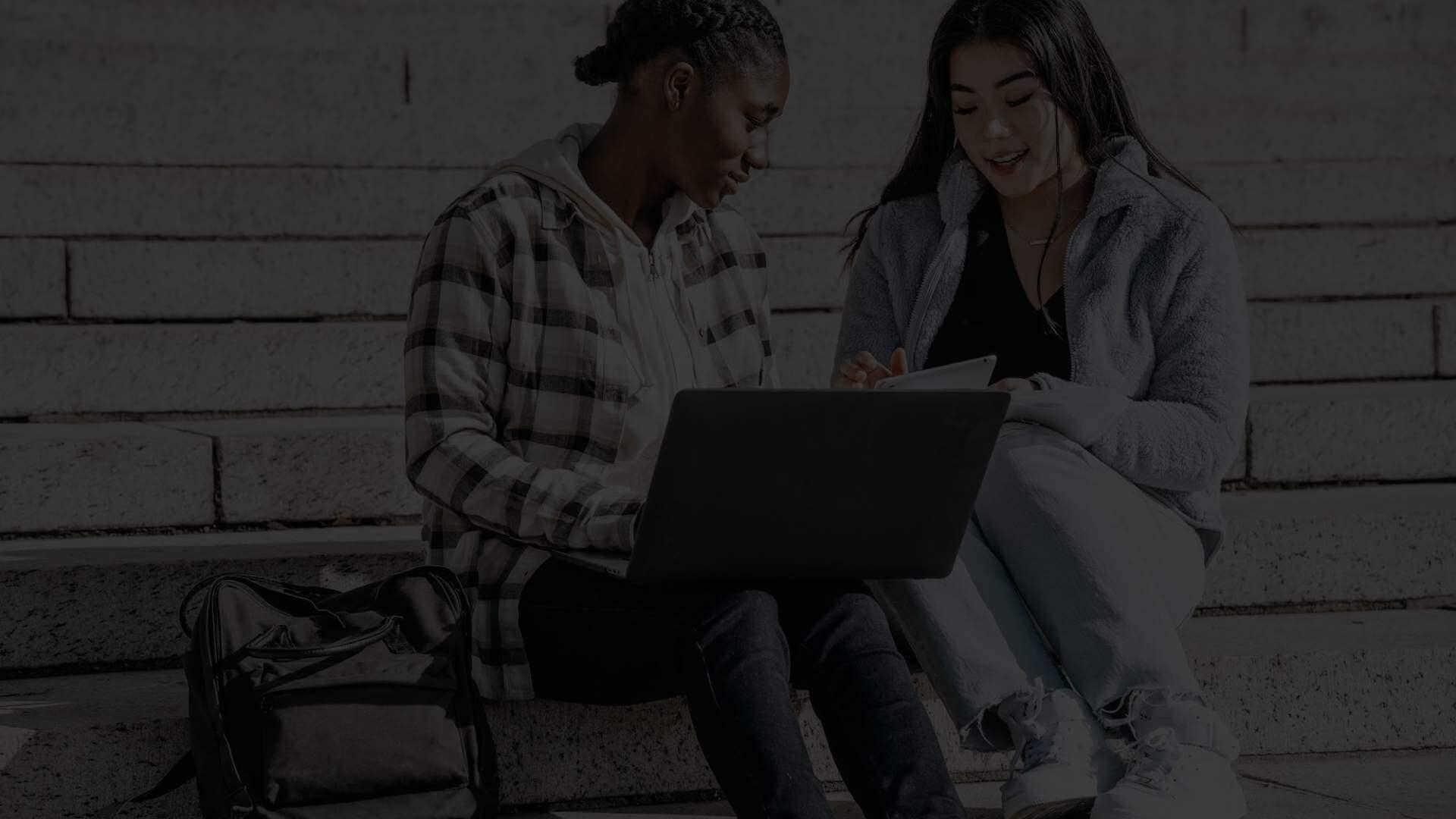 two women learning online in campus