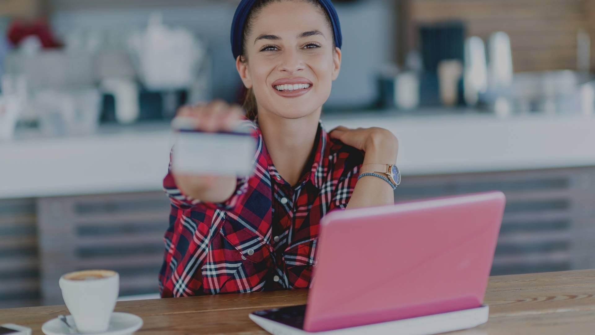 woman in front of her laptop holding her credit card in hands
