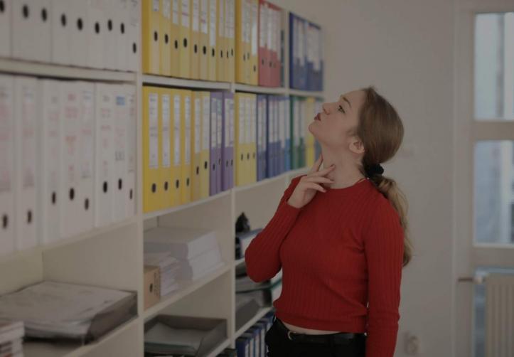 women wearing red tshirt looks at file cabinets at work