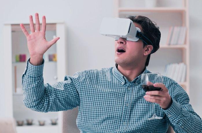 young men at home using VR glasses holding a glass of wine